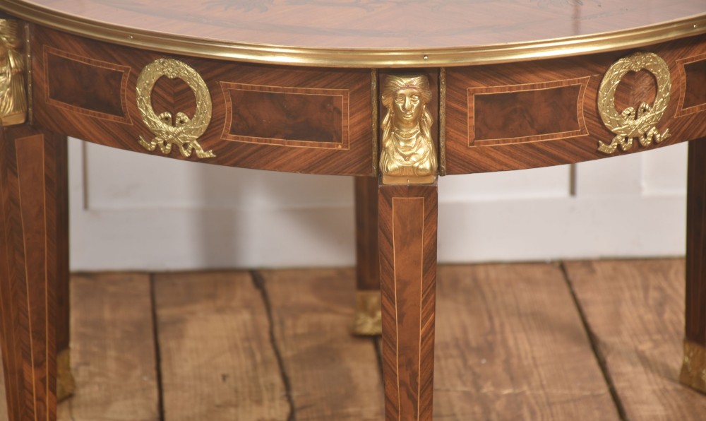 A round Louis XVI style coffee table featuring wood marquetry, warm brown veneers, tapered square legs, and decorative gilt brass female bust mounts. View III