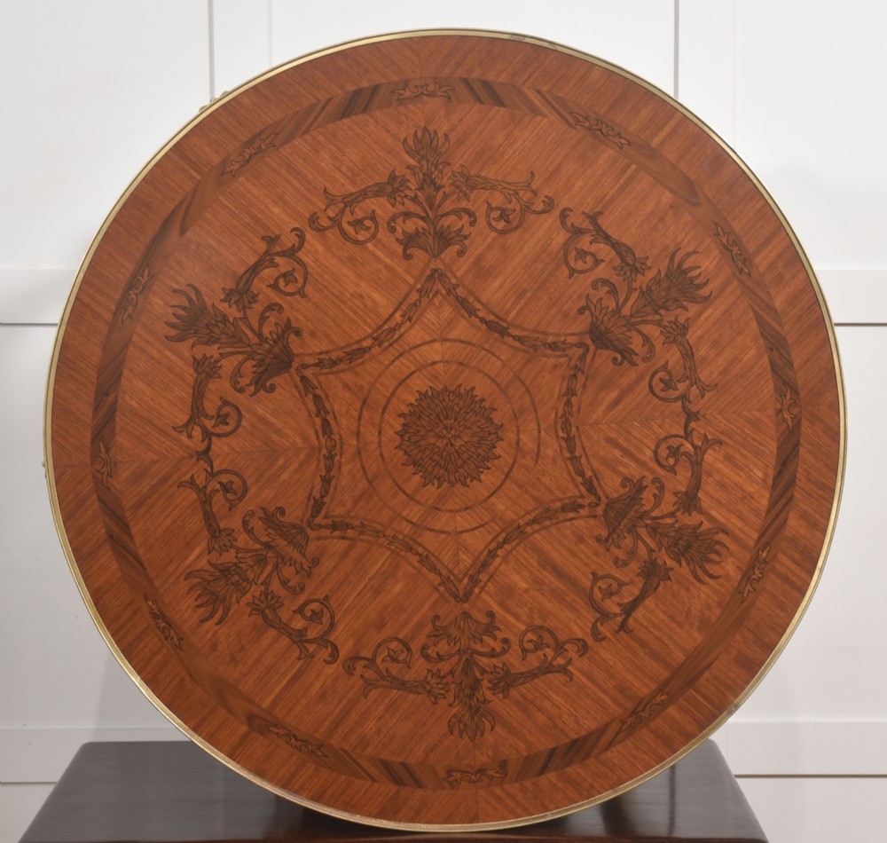 A round Louis XVI style coffee table featuring wood marquetry, warm brown veneers, tapered square legs, and decorative gilt brass female bust mounts. View XI