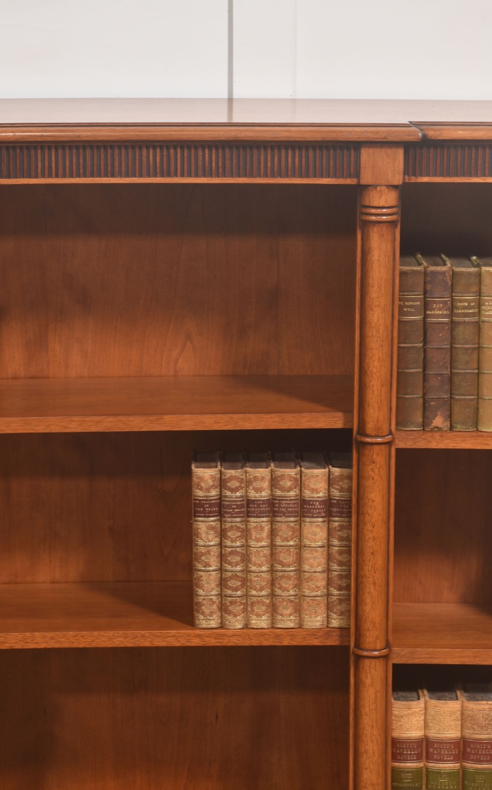 A low Regency style mahogany breakfront open bookcase featuring three shelving sections separated by reeded pilasters. View III