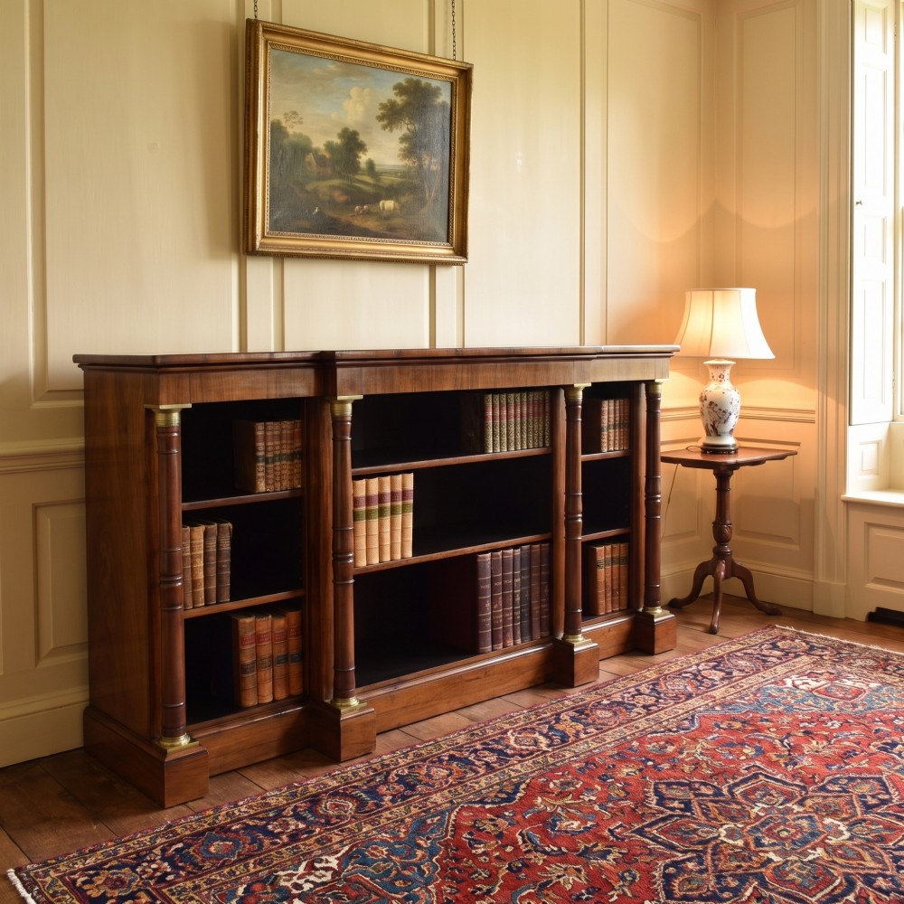 A Regency period open breakfront bookcase crafted from dark rosewood with brass mounted column pilasters and adjustable shelves. View II