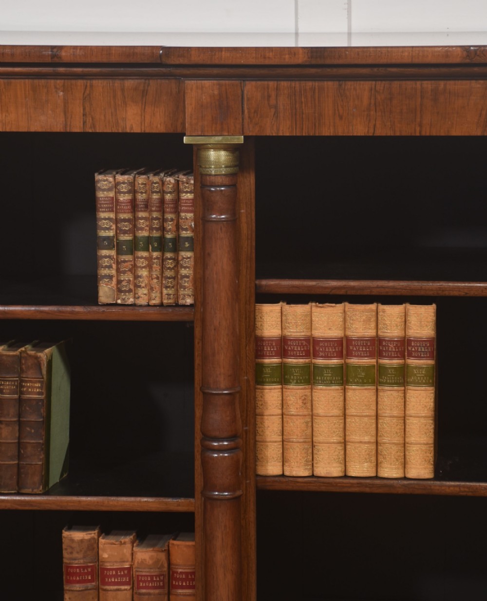 A Regency period open breakfront bookcase crafted from dark rosewood with brass mounted column pilasters and adjustable shelves. View V