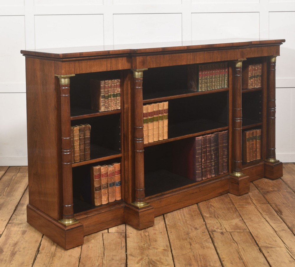 A Regency period open breakfront bookcase crafted from dark rosewood with brass mounted column pilasters and adjustable shelves. View VI
