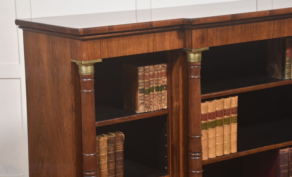 A Regency period open breakfront bookcase crafted from dark rosewood with brass mounted column pilasters and adjustable shelves. View VIII