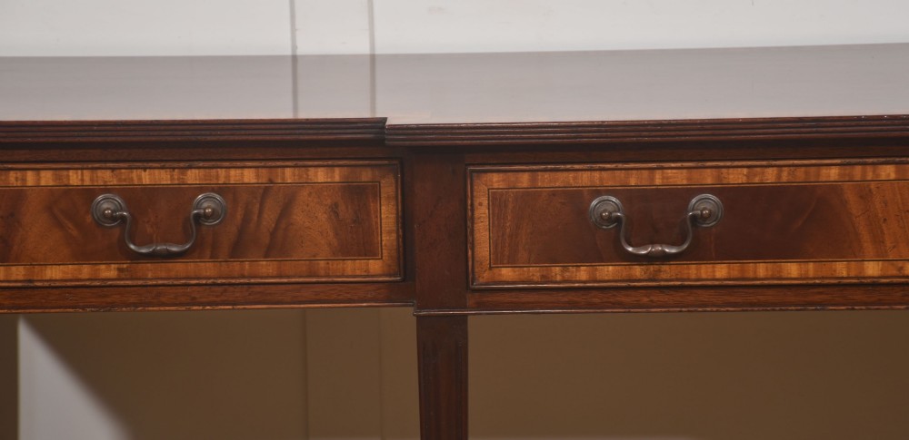 A mahogany breakfront hall table featuring satinwood crossbanding, three drawers with brass handles, and four tapered square legs. View III