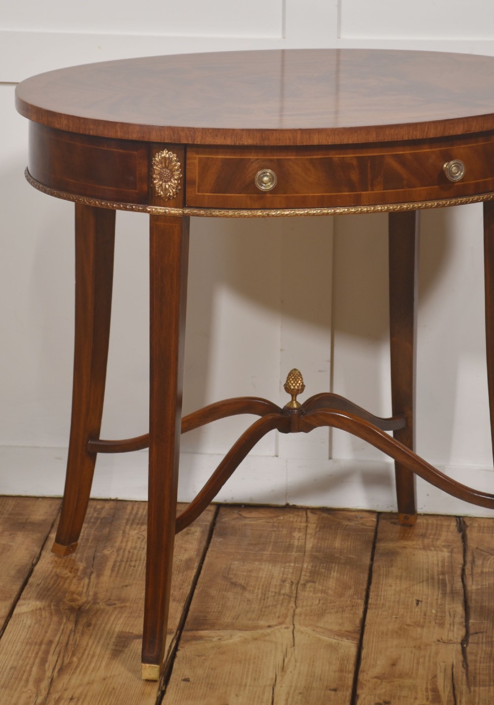 A pair of oval flame mahogany side tables featuring brass rosette mounts, single drawers, curved legs, and an X-shaped stretcher with a brass finial. View III