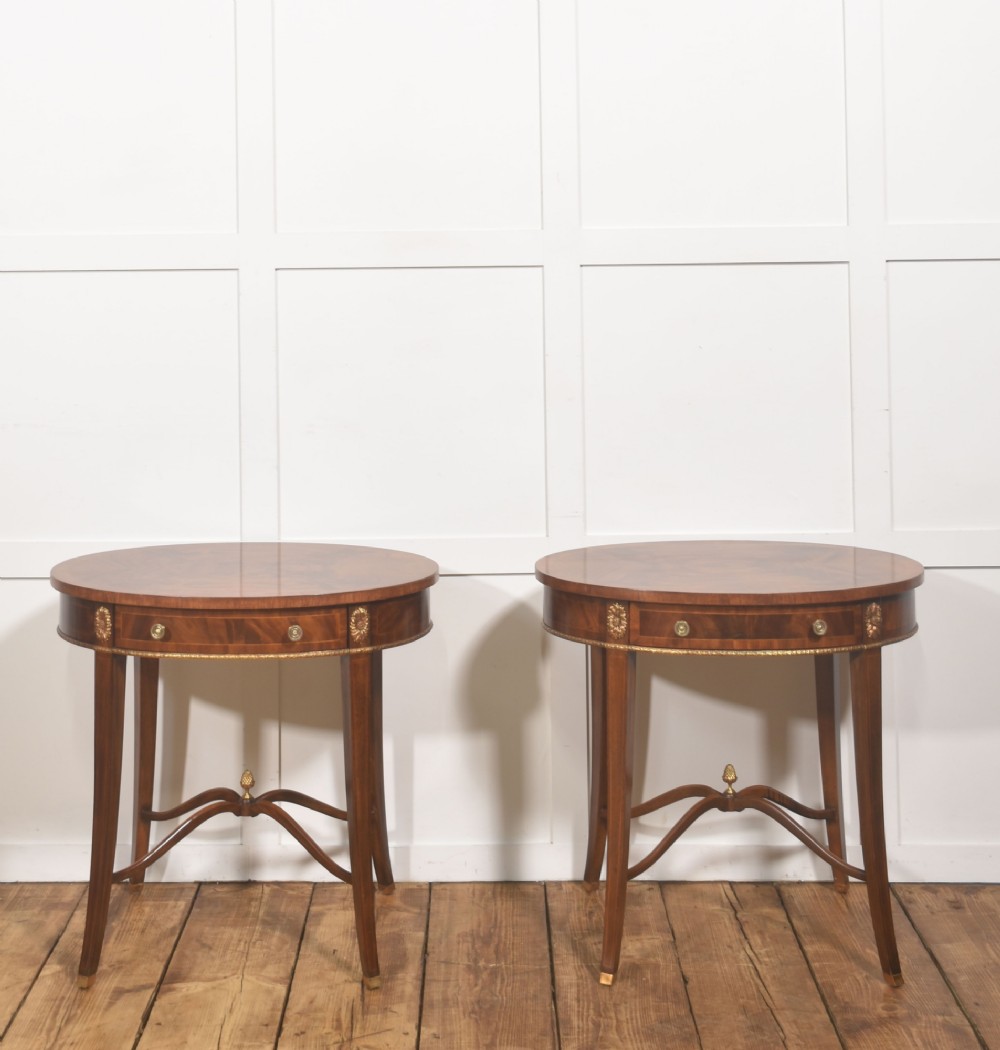 A pair of oval flame mahogany side tables featuring brass rosette mounts, single drawers, curved legs, and an X-shaped stretcher with a brass finial. View VIII