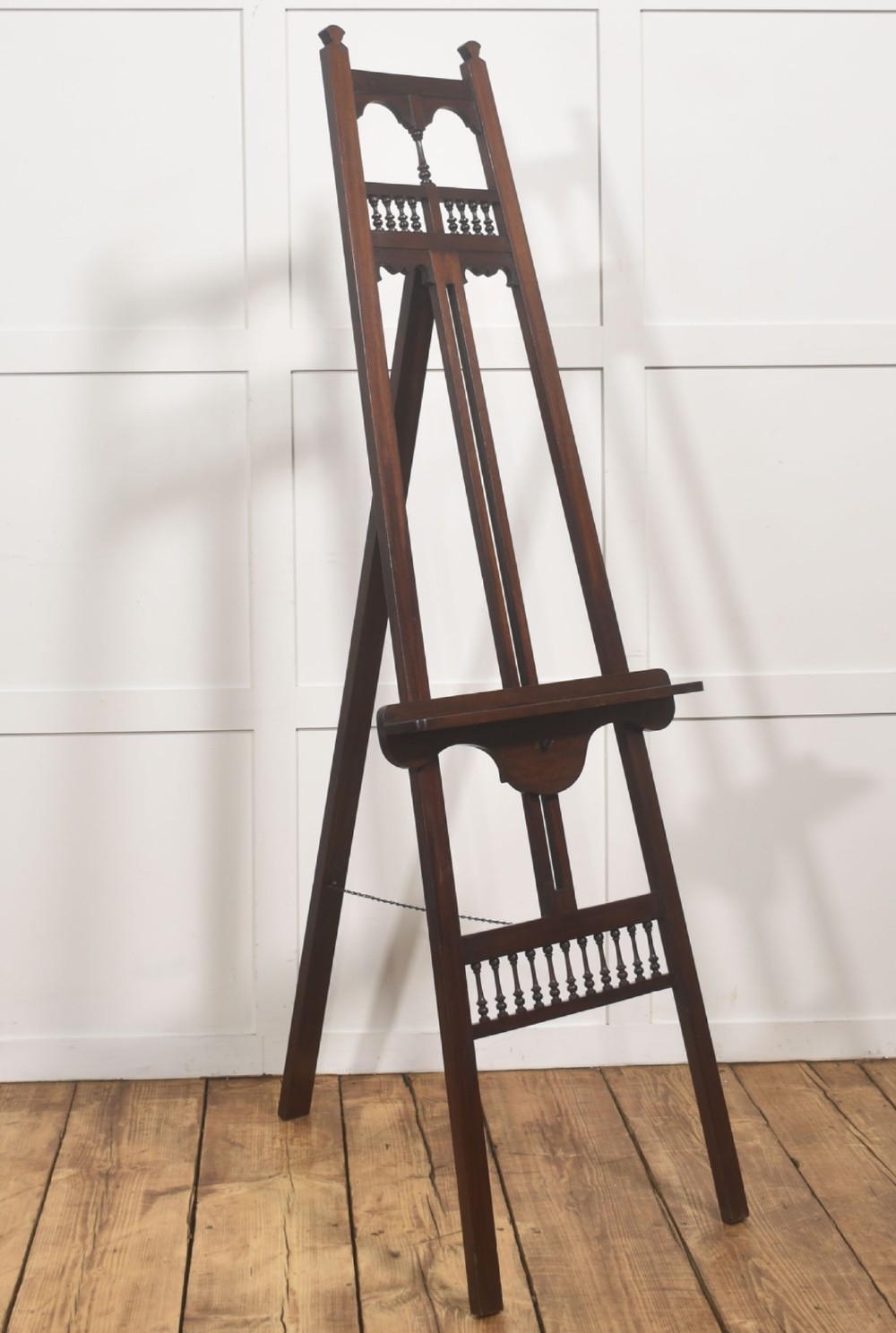 A dark walnut A-frame artist easel featuring Gothic Revival pointed arches, turned spindle galleries, and an adjustable support ledge.