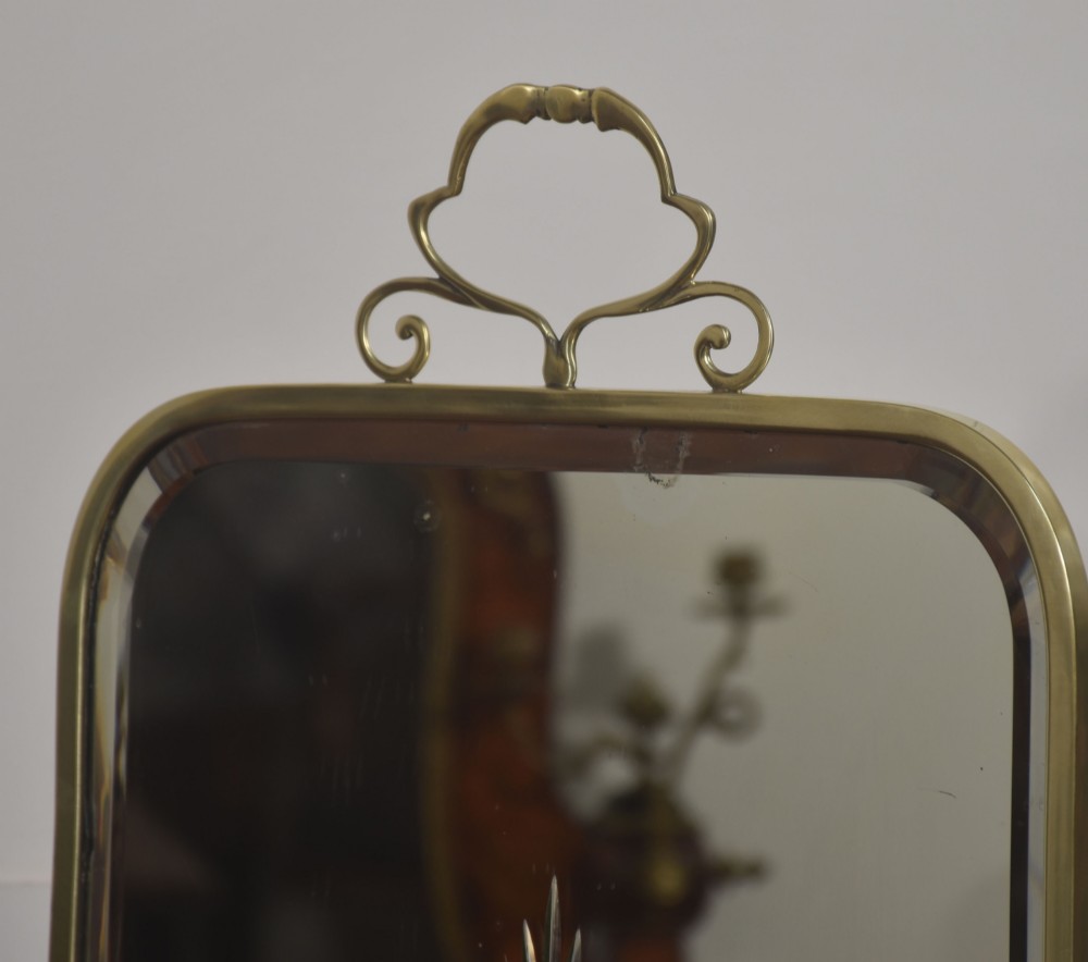 An arched brass-framed fire screen featuring a central cut-glass starburst pattern on a bevelled mirrored panel with a decorative top handle and splayed feet. View VII