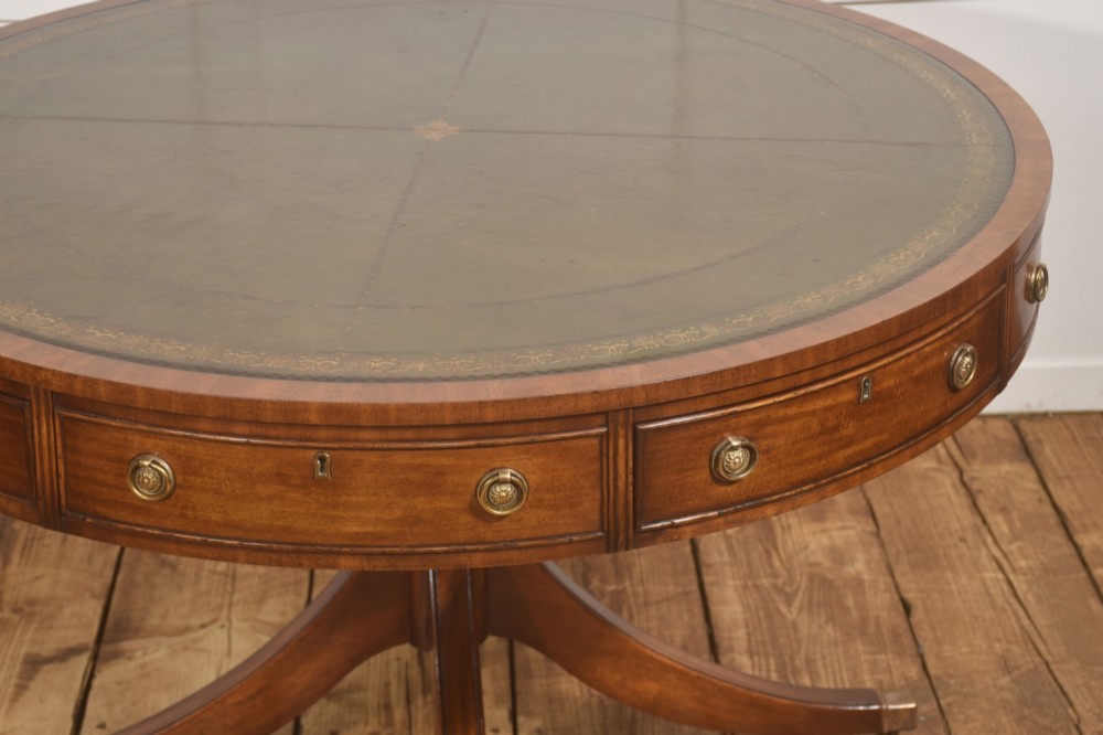 A circular mahogany drum table featuring a green leather top with gold tooling, multiple drawers with brass ring handles, and a four-legged pedestal base on castors. View VIII