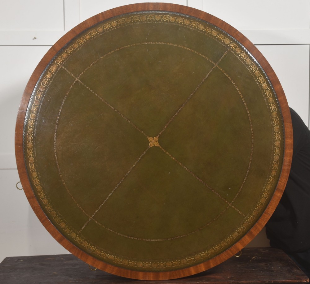 A circular mahogany drum table featuring a green leather top with gold tooling, multiple drawers with brass ring handles, and a four-legged pedestal base on castors. View IX