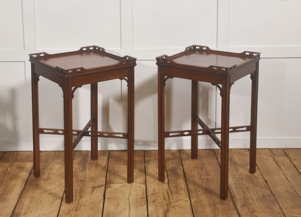 A pair of dark mahogany Edwardian side tables with square tops, pierced fretwork galleries, and cross stretchers.