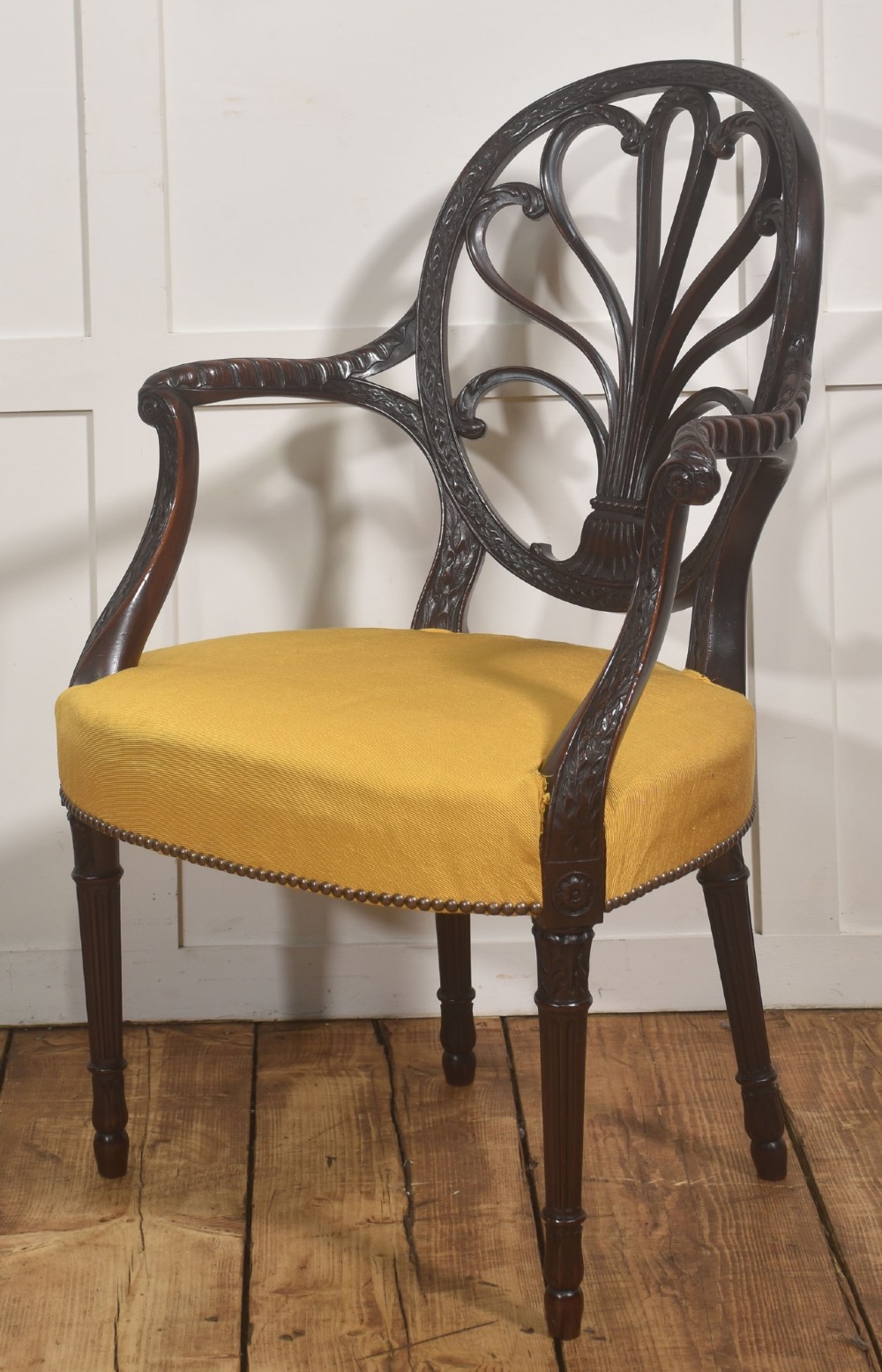 A carved mahogany open armchair featuring an oval wheat-sheaf backrest, swept arms, and a yellow upholstered seat secured with brass studs. View II