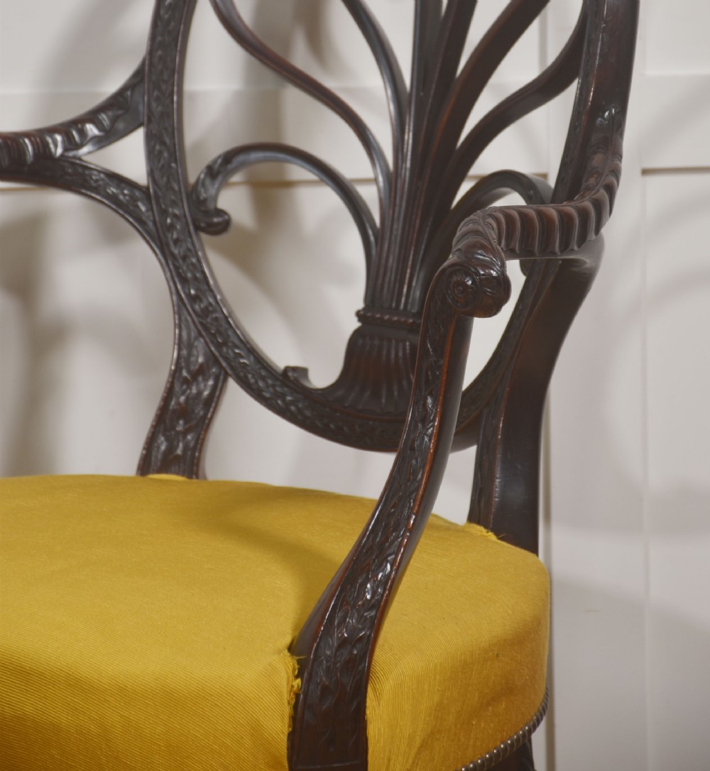 A carved mahogany open armchair featuring an oval wheat-sheaf backrest, swept arms, and a yellow upholstered seat secured with brass studs. View IV