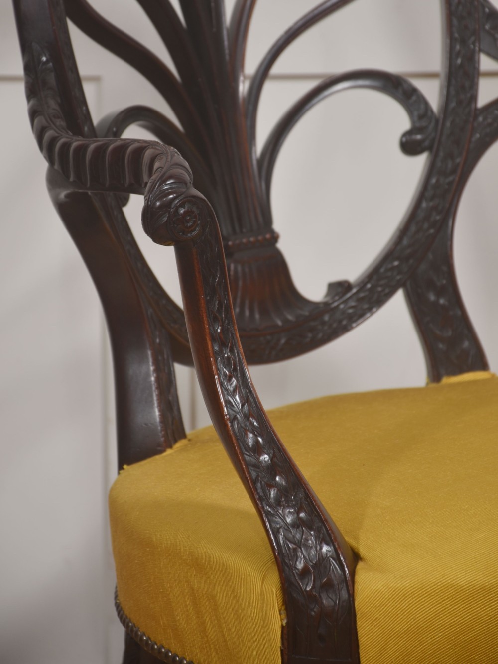 A carved mahogany open armchair featuring an oval wheat-sheaf backrest, swept arms, and a yellow upholstered seat secured with brass studs. View VII