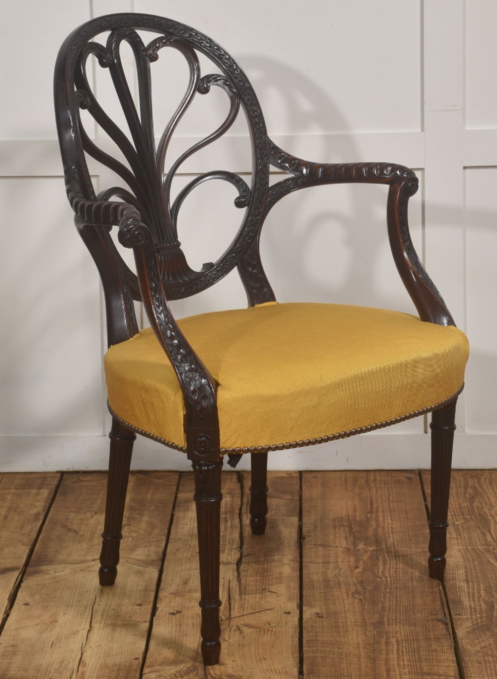 A carved mahogany open armchair featuring an oval wheat-sheaf backrest, swept arms, and a yellow upholstered seat secured with brass studs. View IX
