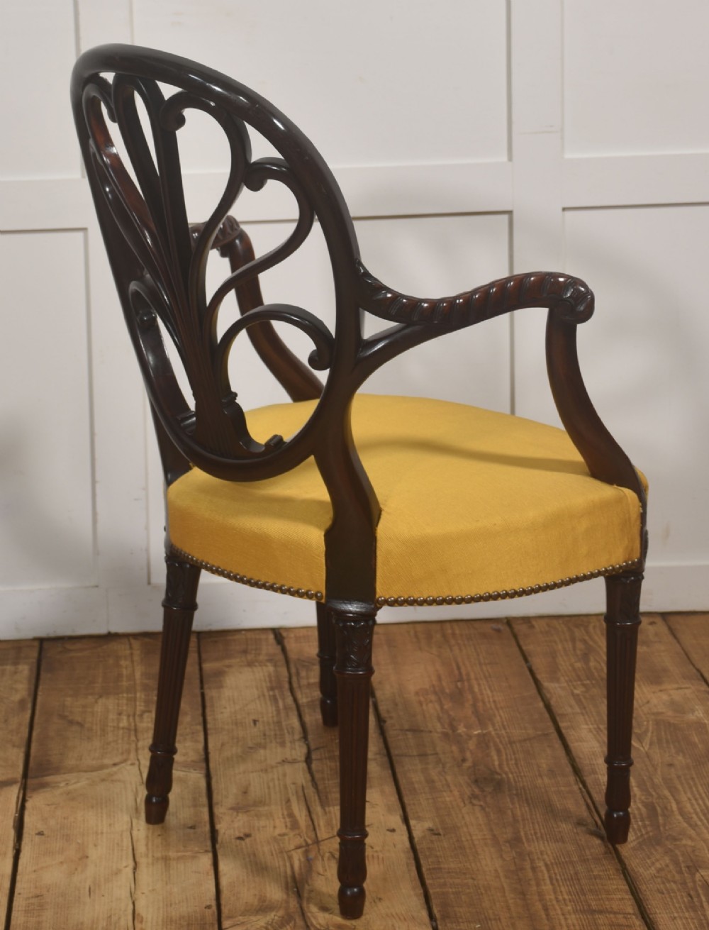 A carved mahogany open armchair featuring an oval wheat-sheaf backrest, swept arms, and a yellow upholstered seat secured with brass studs. View XII