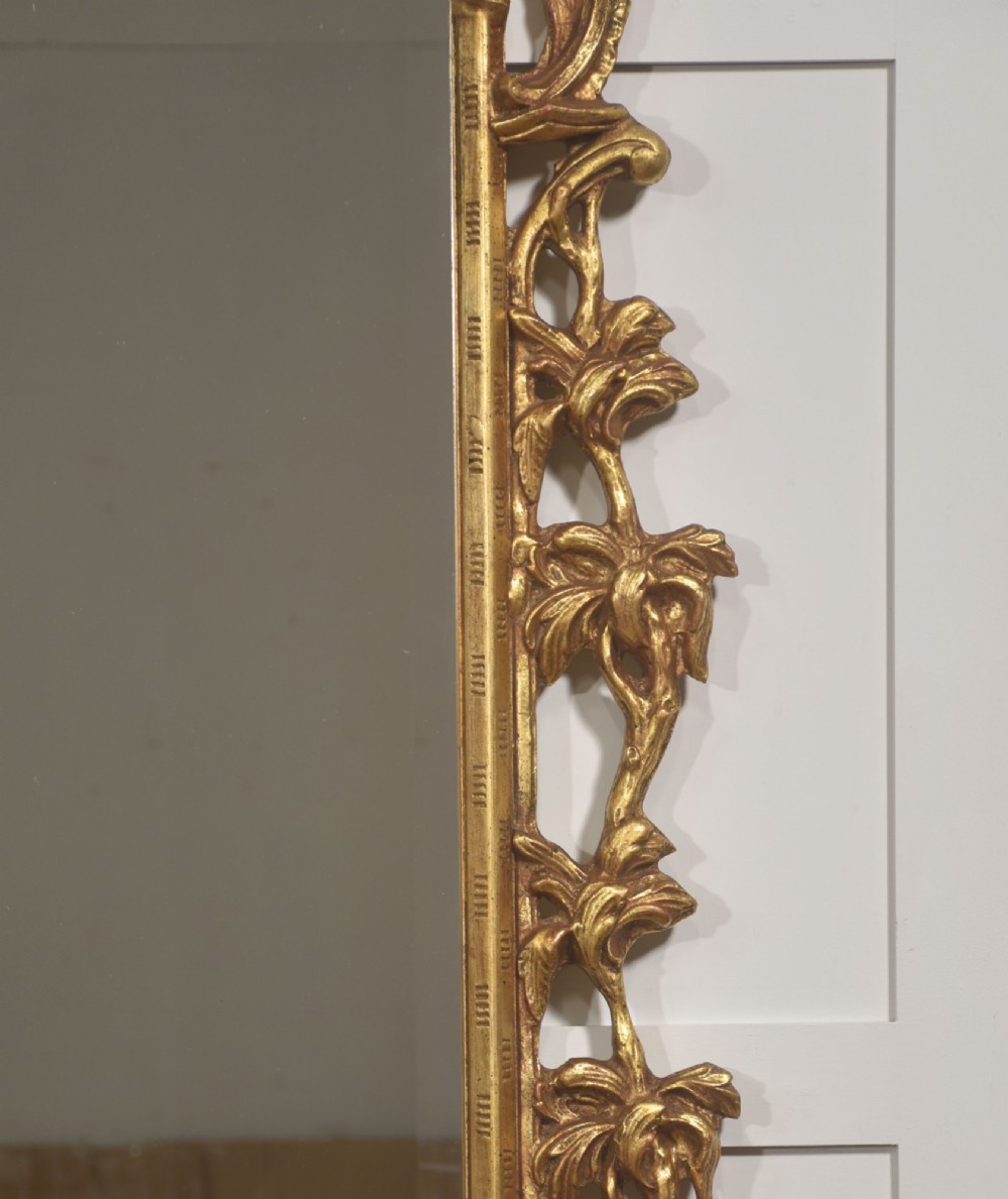 A rectangular wall mirror with a bevelled glass edge framed in elaborate carved gold giltwood featuring scrolls and acanthus motifs. View III