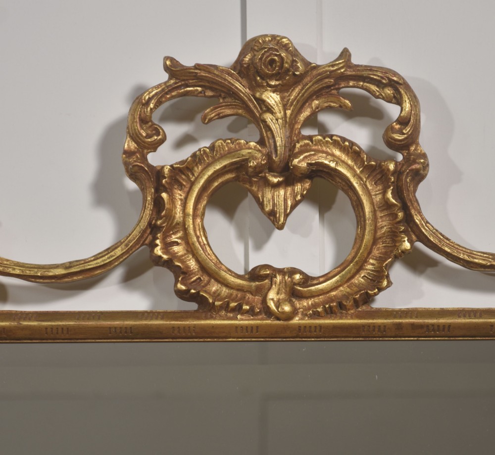A rectangular wall mirror with a bevelled glass edge framed in elaborate carved gold giltwood featuring scrolls and acanthus motifs. View IV