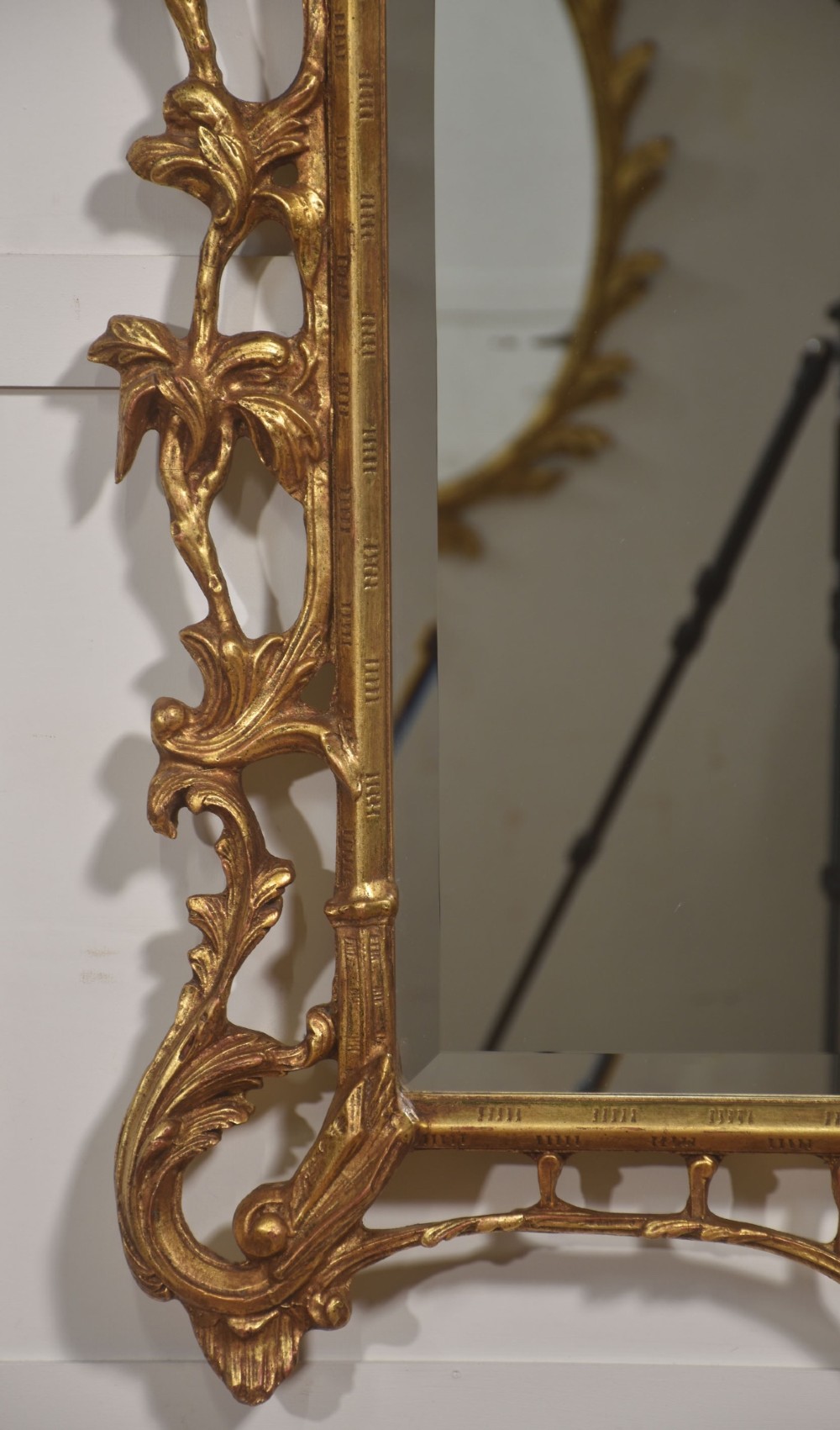 A rectangular wall mirror with a bevelled glass edge framed in elaborate carved gold giltwood featuring scrolls and acanthus motifs. View V