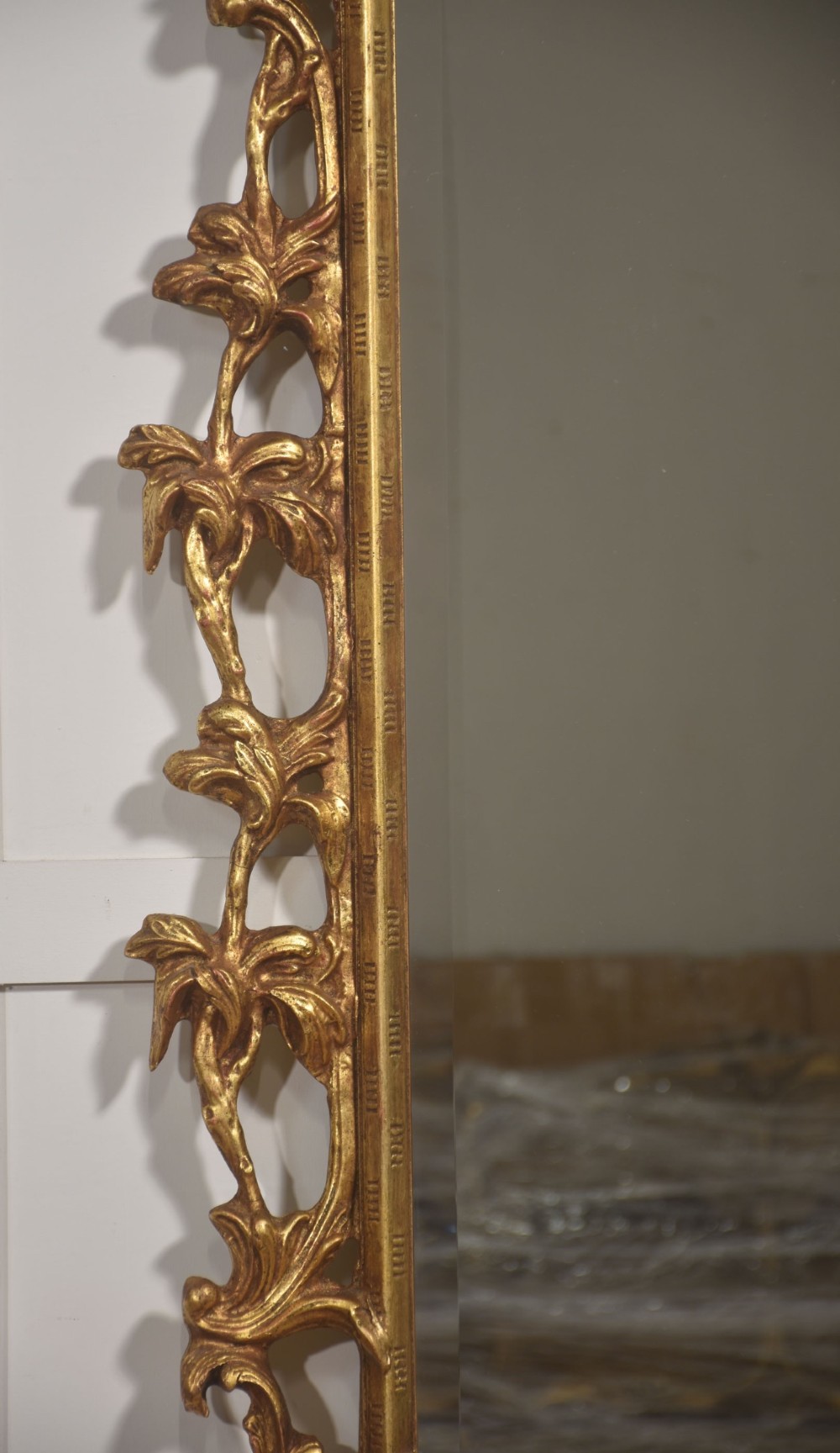 A rectangular wall mirror with a bevelled glass edge framed in elaborate carved gold giltwood featuring scrolls and acanthus motifs. View VI