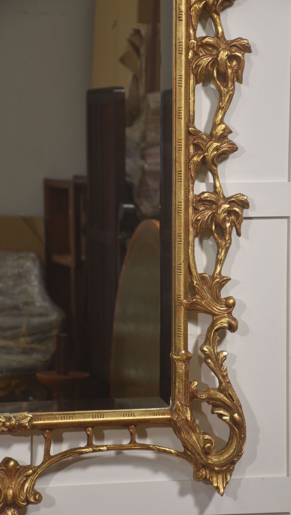 A rectangular wall mirror with a bevelled glass edge framed in elaborate carved gold giltwood featuring scrolls and acanthus motifs. View VII
