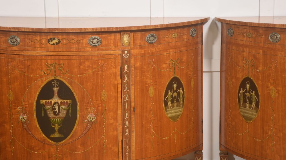 A pair of golden satinwood demi-lune cabinets featuring central hand-painted oval urn motifs and tapered legs. View III