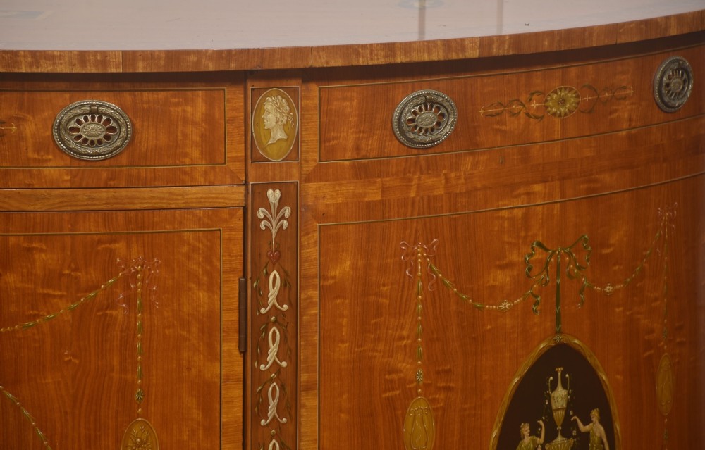 A pair of golden satinwood demi-lune cabinets featuring central hand-painted oval urn motifs and tapered legs. View V
