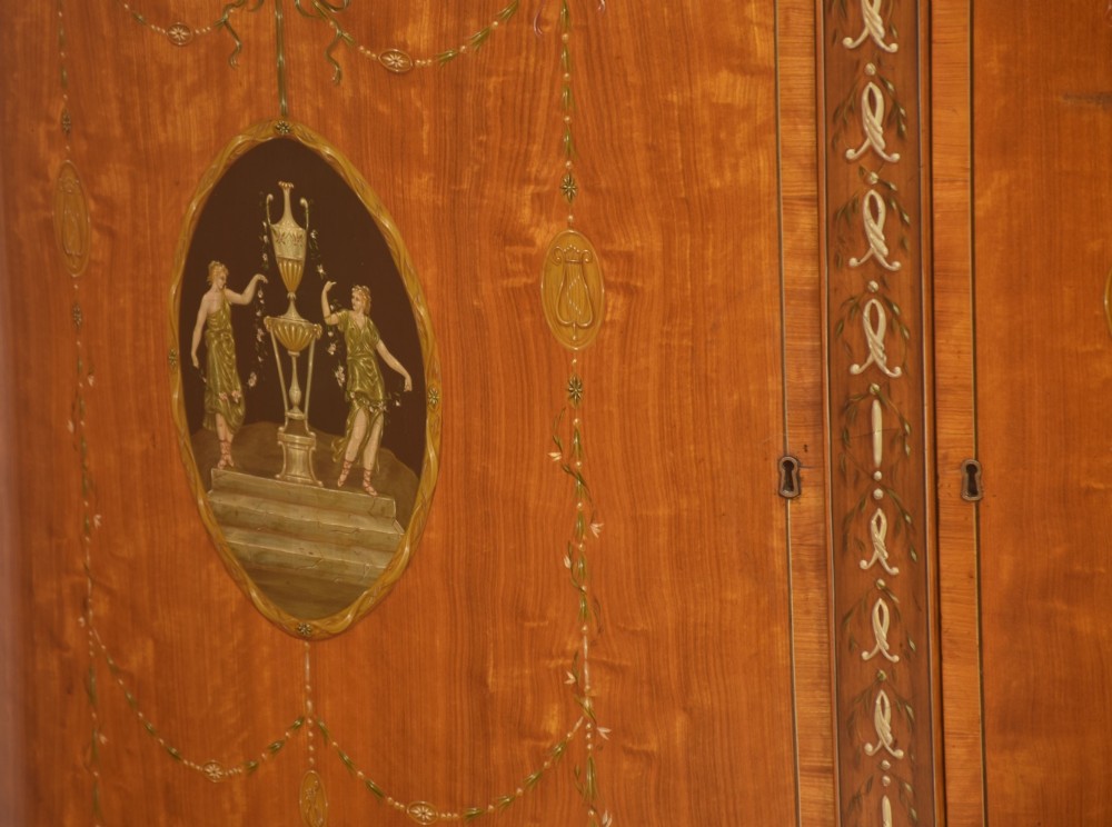 A pair of golden satinwood demi-lune cabinets featuring central hand-painted oval urn motifs and tapered legs. View VI