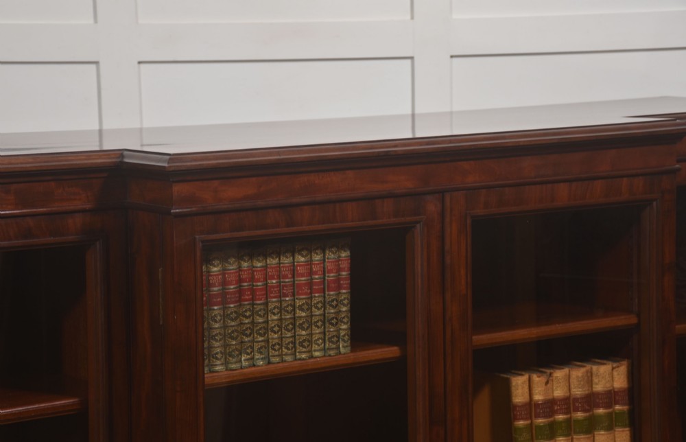 A 19th-century mahogany breakfront library bookcase featuring four glass-panelled doors, adjustable interior shelving, and a moulded cornice. View VIII