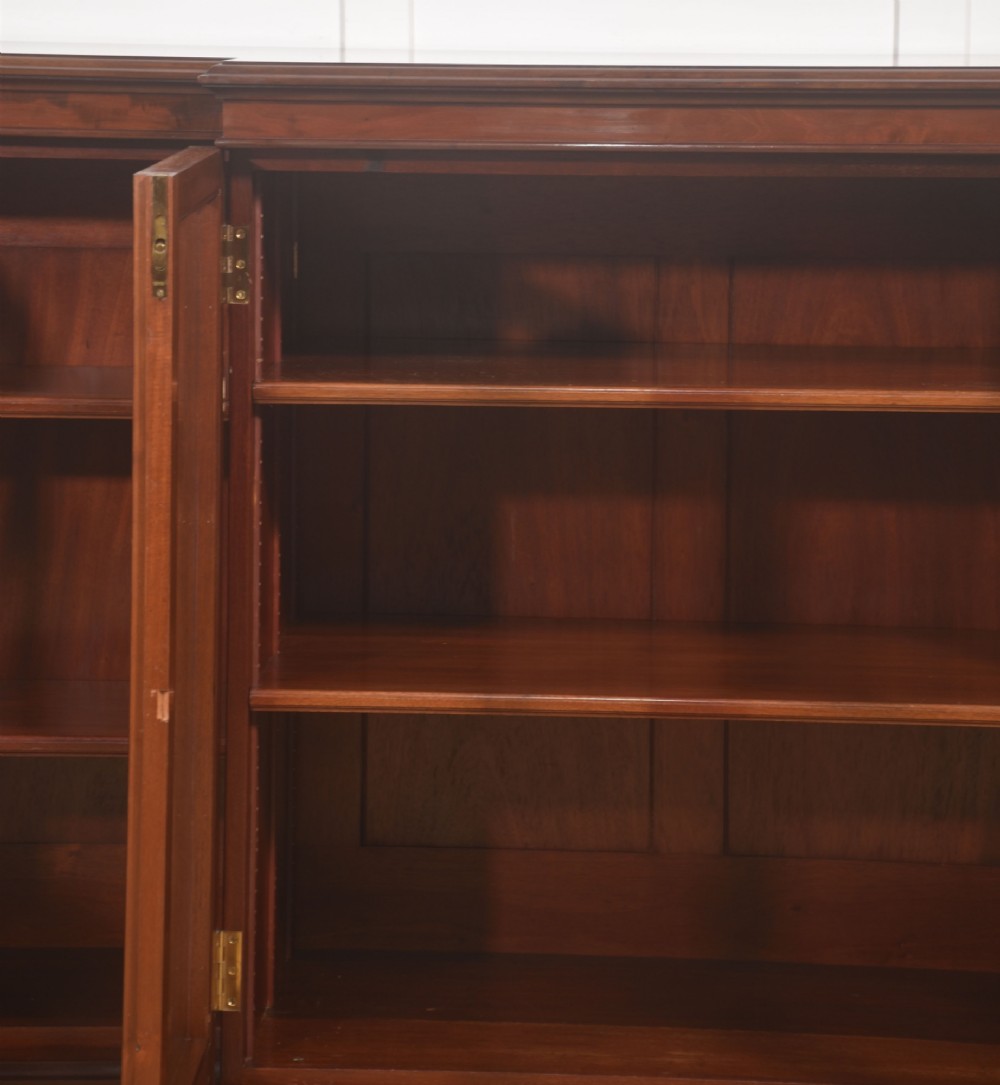 A 19th-century mahogany breakfront library bookcase featuring four glass-panelled doors, adjustable interior shelving, and a moulded cornice. View X