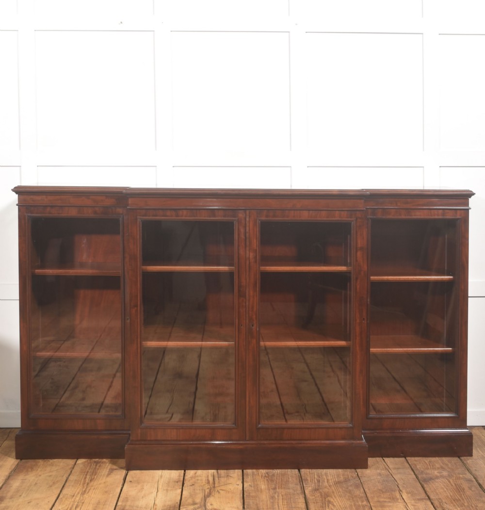 A 19th-century mahogany breakfront library bookcase featuring four glass-panelled doors, adjustable interior shelving, and a moulded cornice. View XI