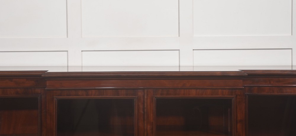 A 19th-century mahogany breakfront library bookcase featuring four glass-panelled doors, adjustable interior shelving, and a moulded cornice. View XII