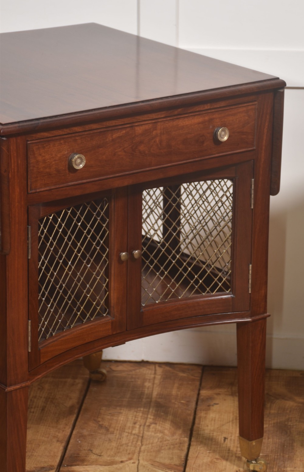 A pair of rosewood drop-leaf side tables featuring single drawers above cupboard doors with brass grille inserts, standing on square tapered legs with brass castors. View II