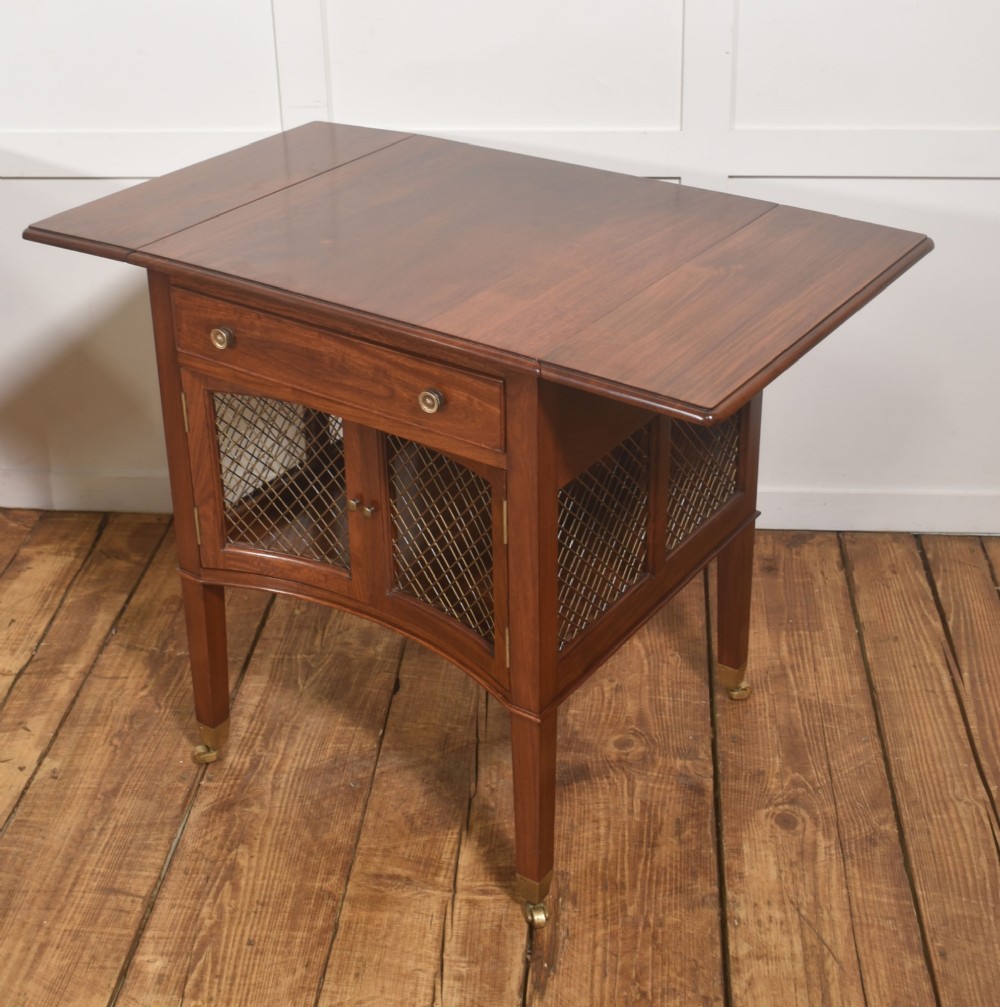 A pair of rosewood drop-leaf side tables featuring single drawers above cupboard doors with brass grille inserts, standing on square tapered legs with brass castors. View IV