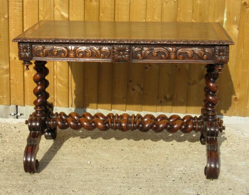 fig 1. A late 19th-century dark oak writing table featuring relief-carved drawer fronts, barley twist legs, and a double twisted stretcher.