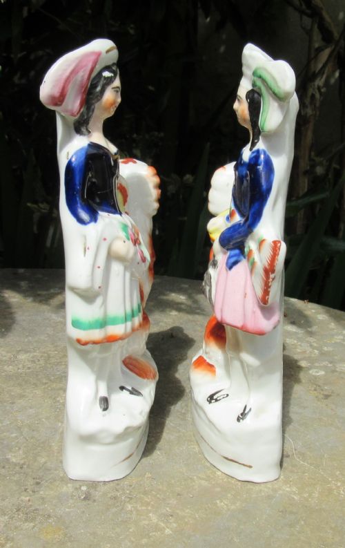 fig 1. A pair of Victorian Staffordshire glazed earthenware figures depicting a male and female musician dressed in traditional attire, each accompanied by a white and orange spaniel.