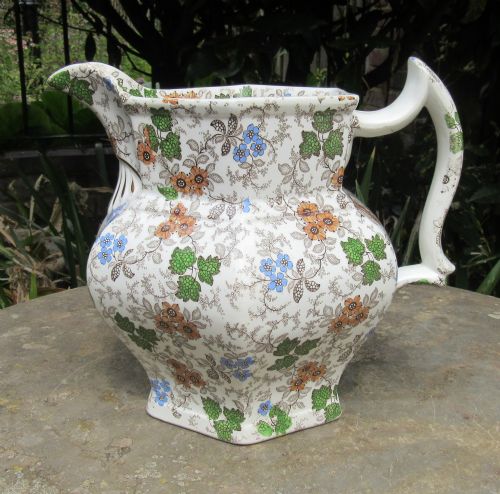 fig 1. An octagonal white ceramic jug with colourful floral transferware, a moulded gilt shell detail, and handwritten gold lettering dated September 27 1839.
