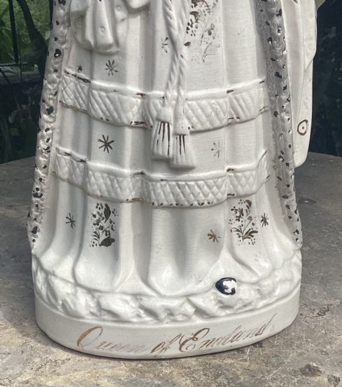 fig 1. A Victorian Staffordshire earthenware figure depicting Queen Victoria wearing a crown, veil, and blue sash with gilded details.