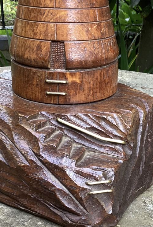fig 1. A solid oak table lamp hand-carved in the shape of a lighthouse resting on a sculpted rocky timber base with a brass fixture at the top.