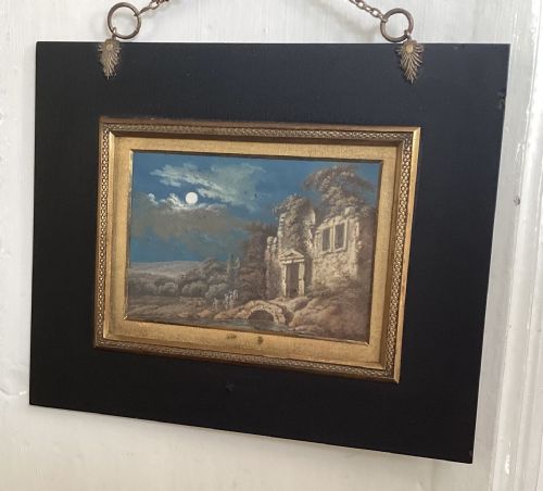 fig 1. A pair of small Georgian paintings depicting architectural ruins in daylight and moonlight, set within wide ebonised frames with gilded borders and hanging chains.