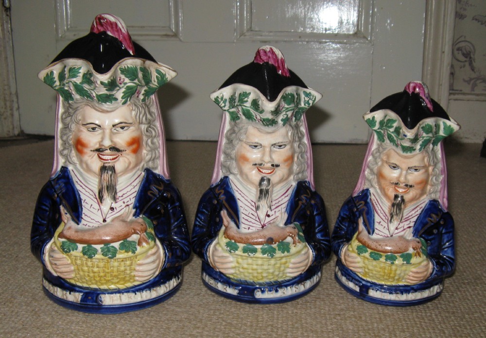 RARE SET OF THREE GRADUATED 'MERRY CHRISTMAS' STAFFORDSHIRE TOBY JUGS c1860