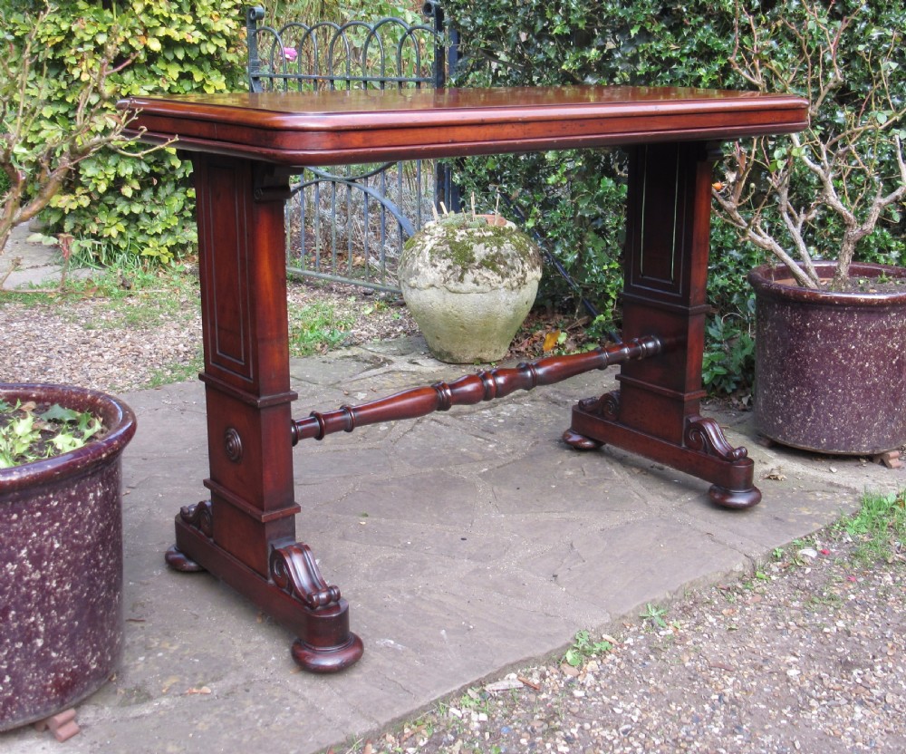 A William IV mahogany metamorphic serving table featuring a smooth rectangular top supported by panelled pedestal ends and a turned central stretcher.