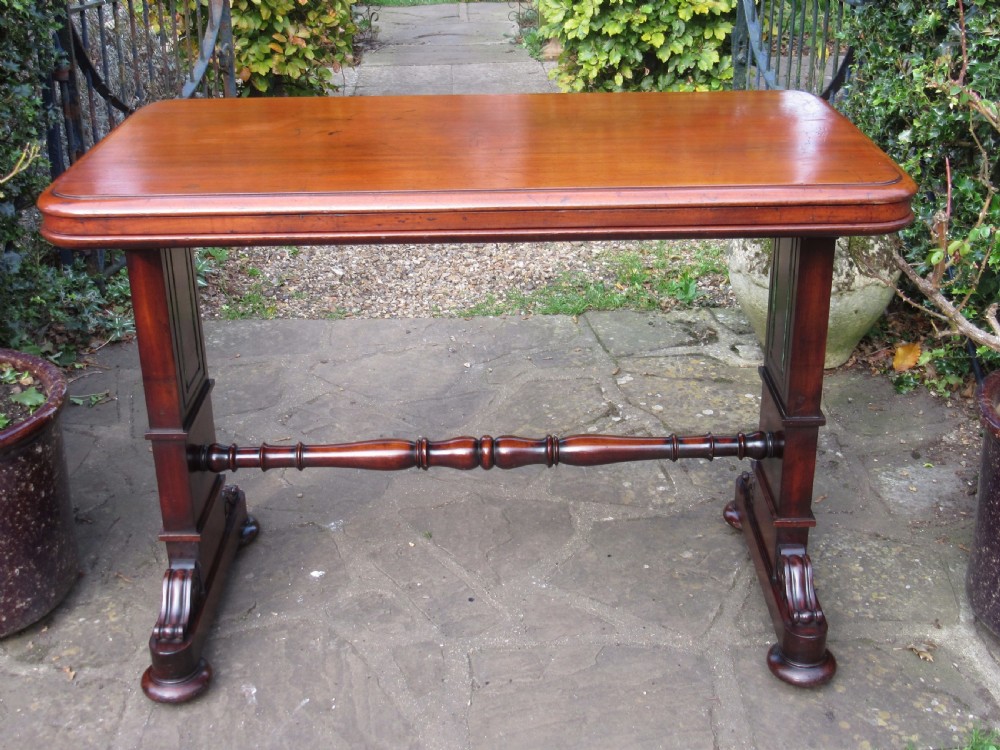 A William IV mahogany metamorphic serving table featuring a smooth rectangular top supported by panelled pedestal ends and a turned central stretcher. View II