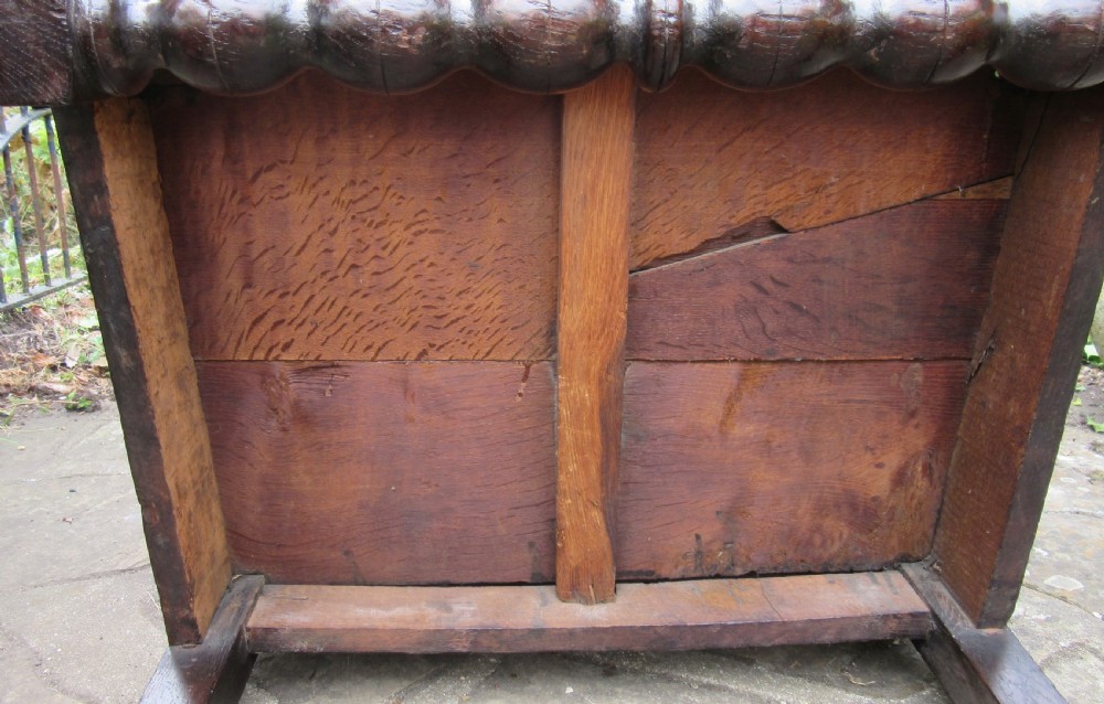 A seventeenth-century dark oak wainscot armchair featuring a carved cresting rail, panelled back, shaped arms, and a bobbin-turned front stretcher. View IX