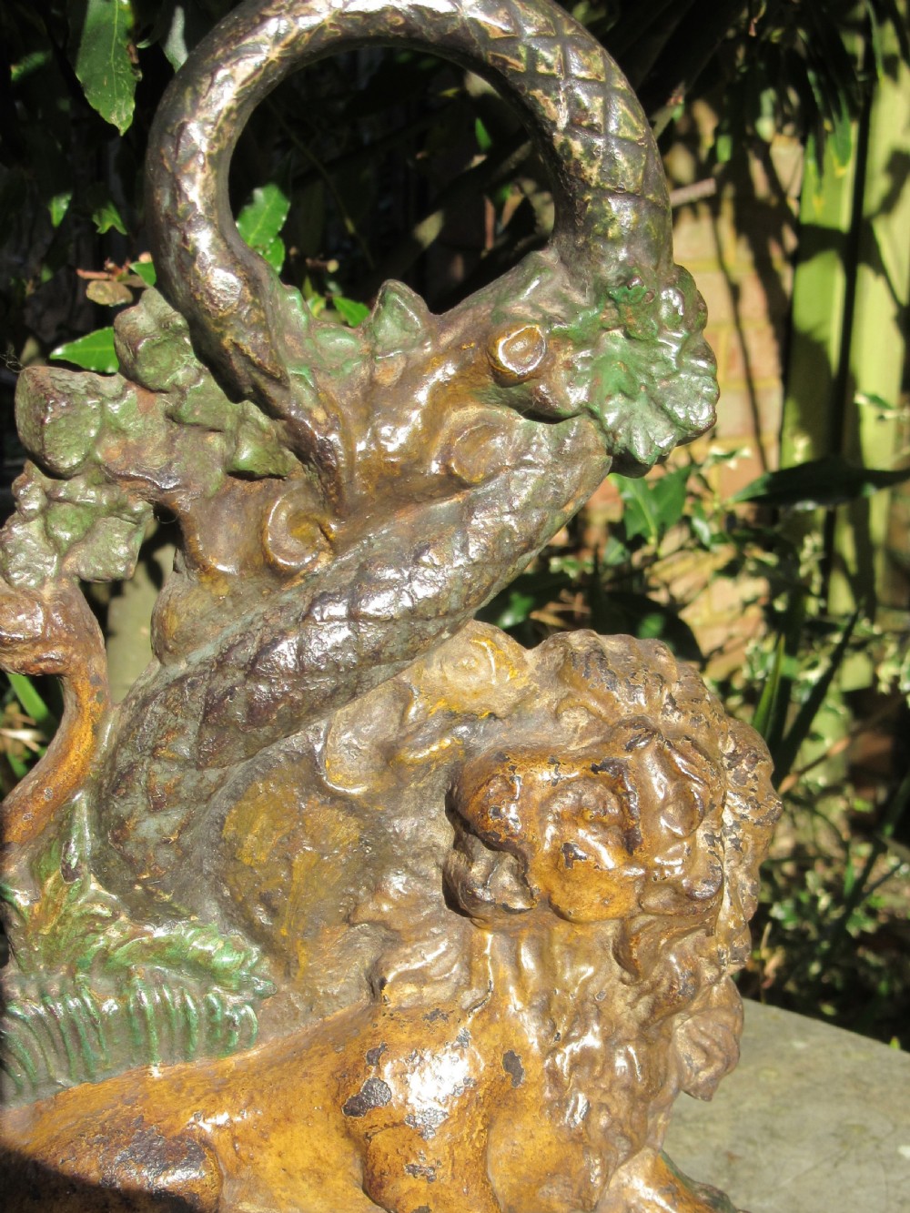 A heavy Georgian cast iron doorstop featuring a sculptural lion at the base with a serpent coiling around a tree trunk to form a loop handle. View II