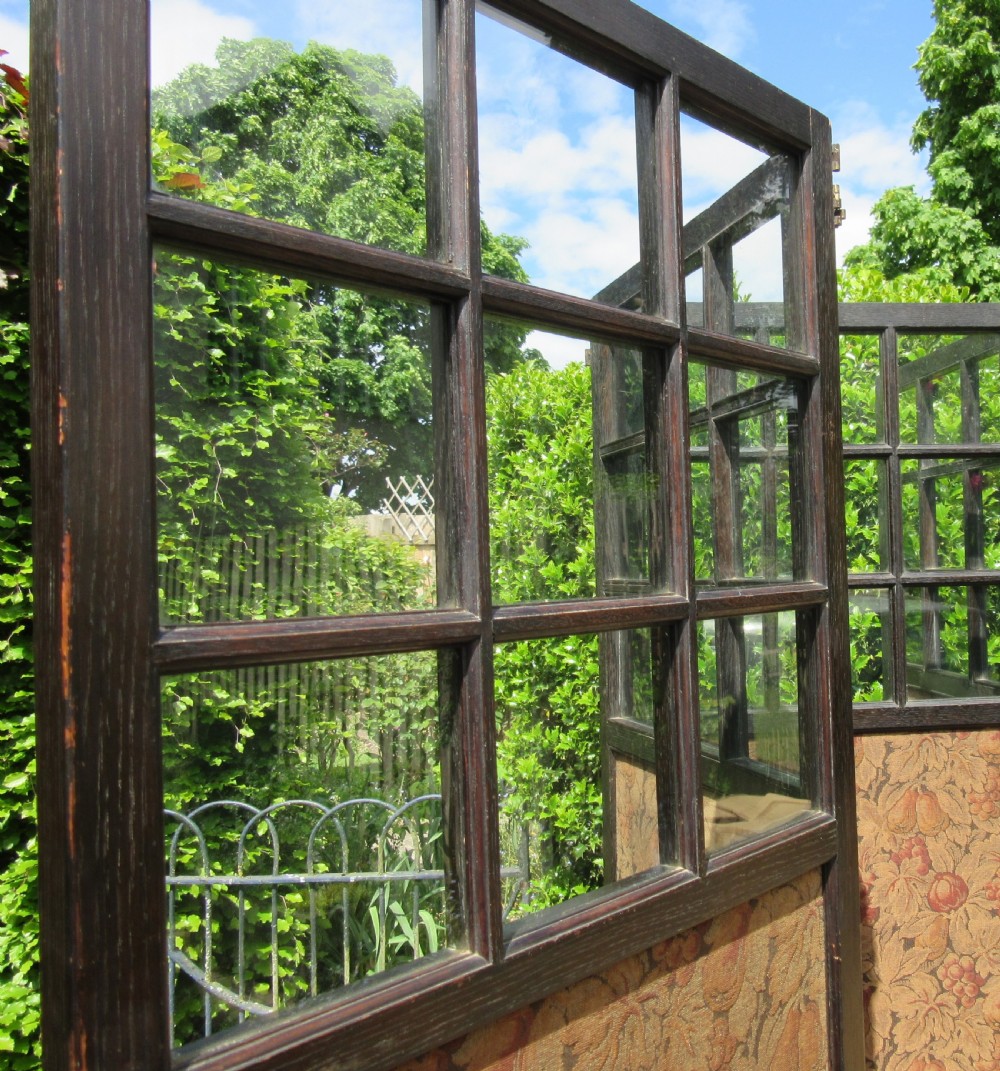 An Arts and Crafts four-panel ebonised oak folding screen featuring six glazed panes at the top of each panel and patterned botanical fabric inserts below. View IV