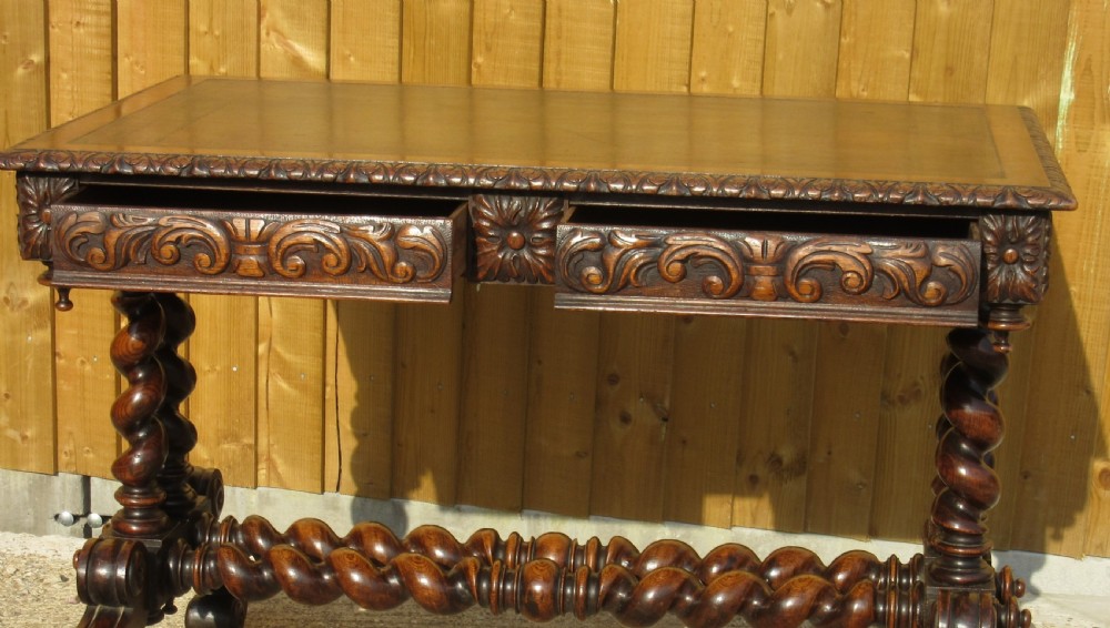 A late 19th-century dark oak writing table featuring relief-carved drawer fronts, barley twist legs, and a double twisted stretcher. View III