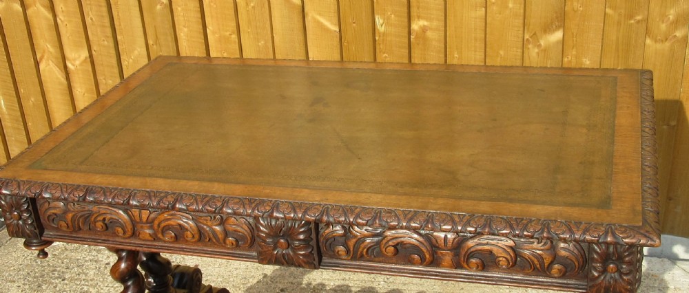 A late 19th-century dark oak writing table featuring relief-carved drawer fronts, barley twist legs, and a double twisted stretcher. View IV