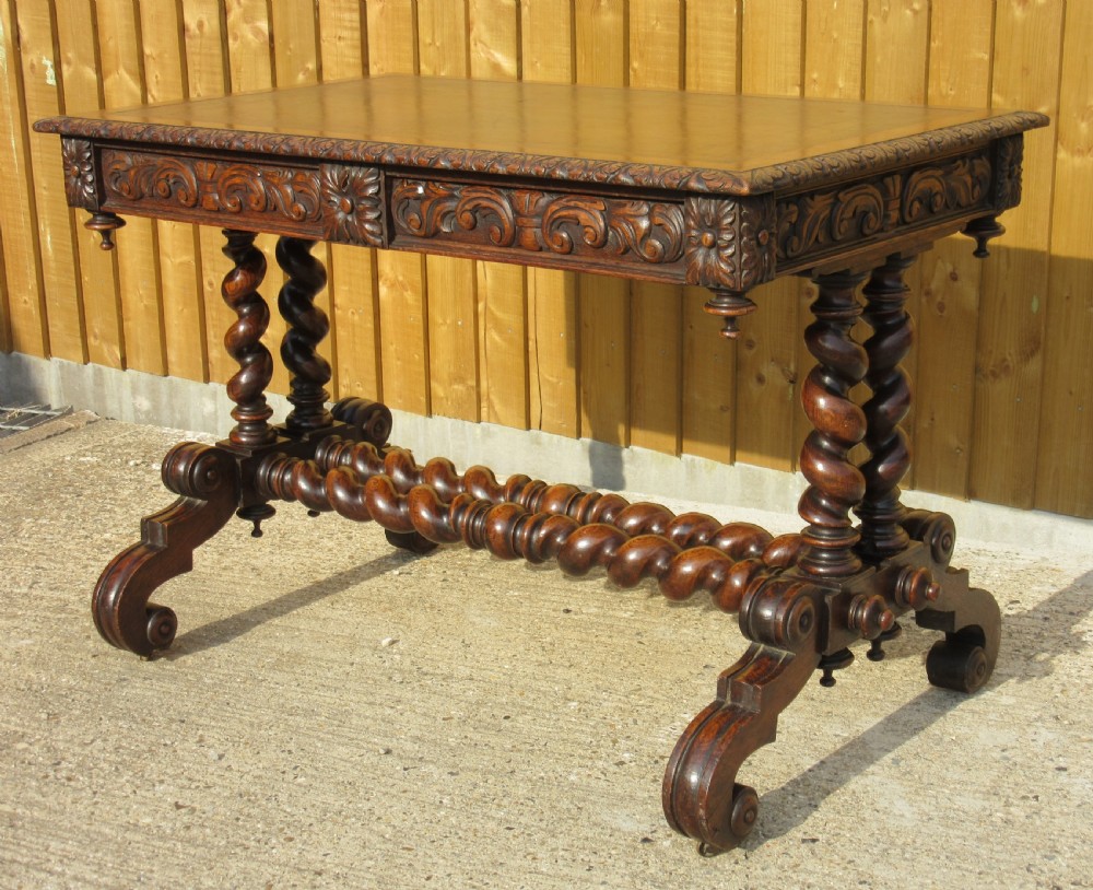 A late 19th-century dark oak writing table featuring relief-carved drawer fronts, barley twist legs, and a double twisted stretcher. View V