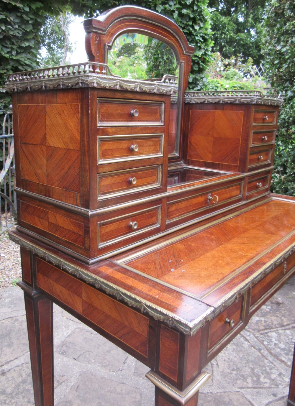 A late 19th-century rosewood bonheur du jour writing desk featuring brass gallery railings, an arched central mirror, multiple small drawers, and tapered legs. View IV